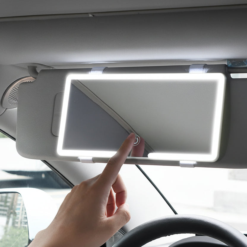 Car visor mirror with touch screen capacitive lighting, hand pointing at it.